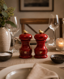 Bisetti Bird red salt and pepper shakers with bird finials on a dining table with wine glasses and a candle.