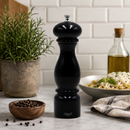 Bisetti firenze black pepper grinder on a kitchen counter with ingredients and a plant in the background.