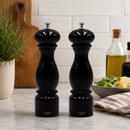 Bisetti black firenze salt and pepper mills on a kitchen counter with a salad and olive oil bottle in the background.