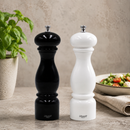 Bisetti black and white salt and pepper mills on a table with a plant and salad in the background