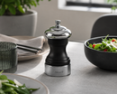 Bisetti messina pepper grinder on a table with a salad and other dishes in the background
