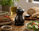 Bisetti pepper grinder on a table with food and bread in the background