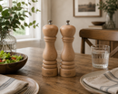 Bisetti roma salt and pepper shakers on a wooden table with a glass of water and salad bowl.